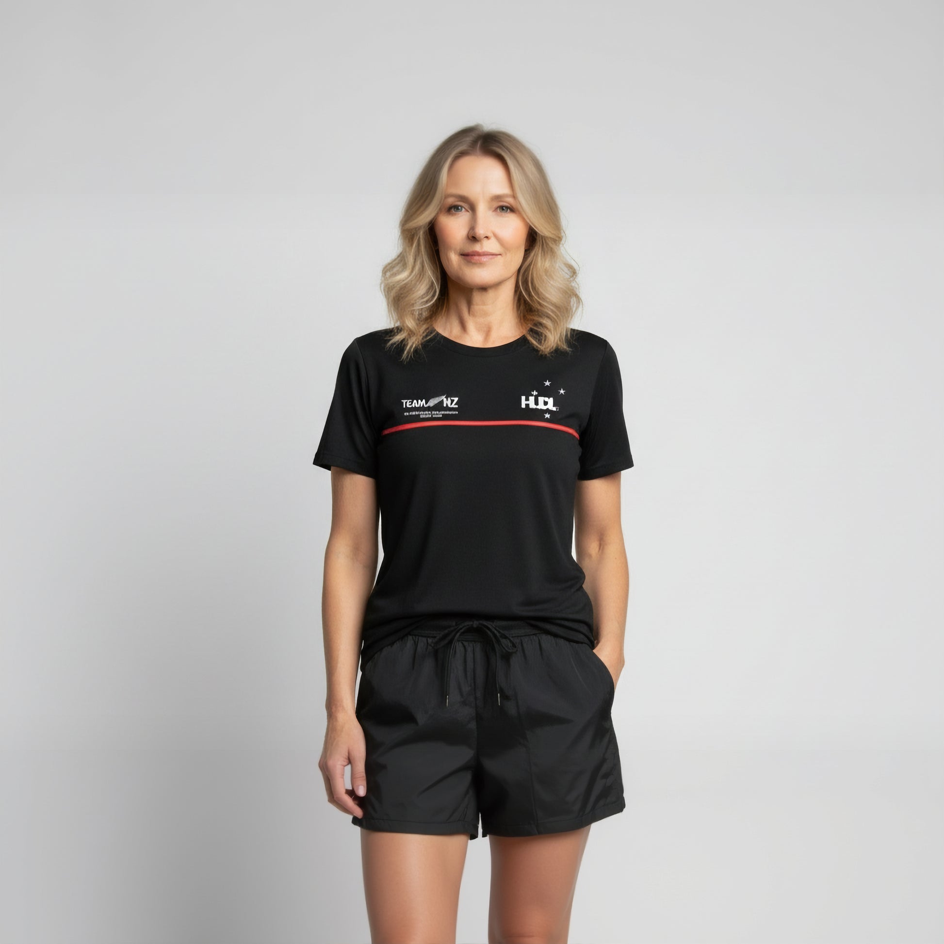 Front view of a womanwearing Paul Coll 2026 team support squash shirt pre-sale – back NZ's finest on court with HUDL Athletica.  