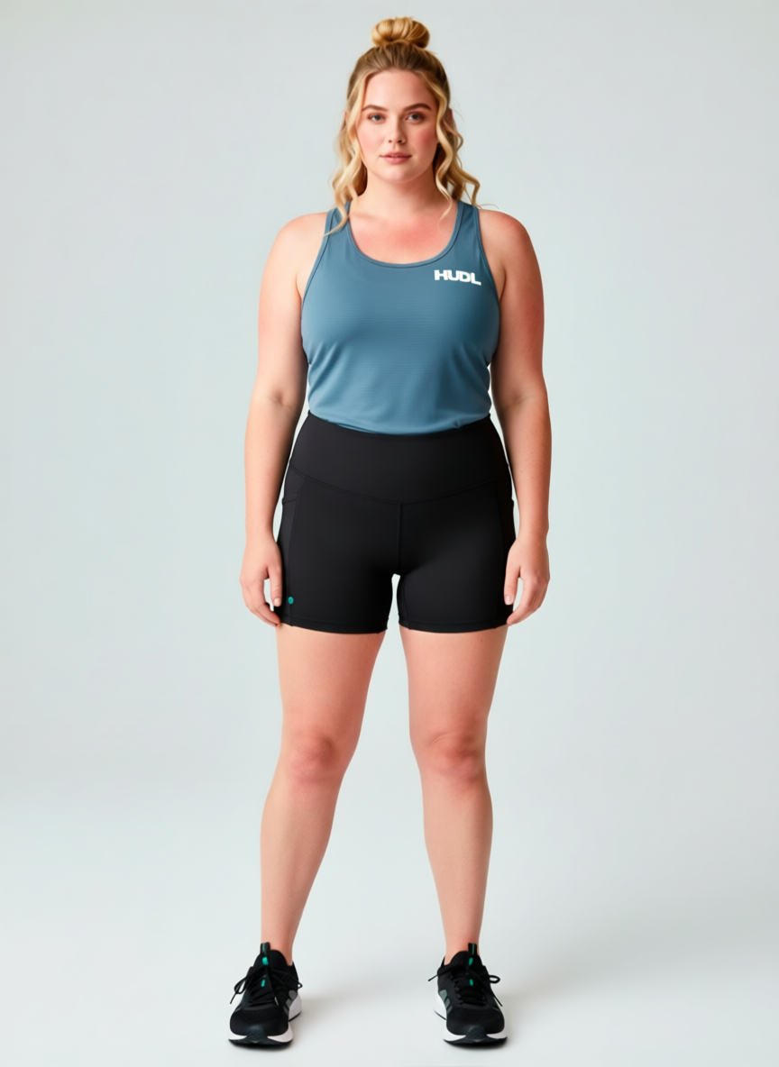 A woman standing  wearing HUDL women's squash biker shorts – XTPro fabric  high-performance fit also wearing the Provincial Blue Scoop next T