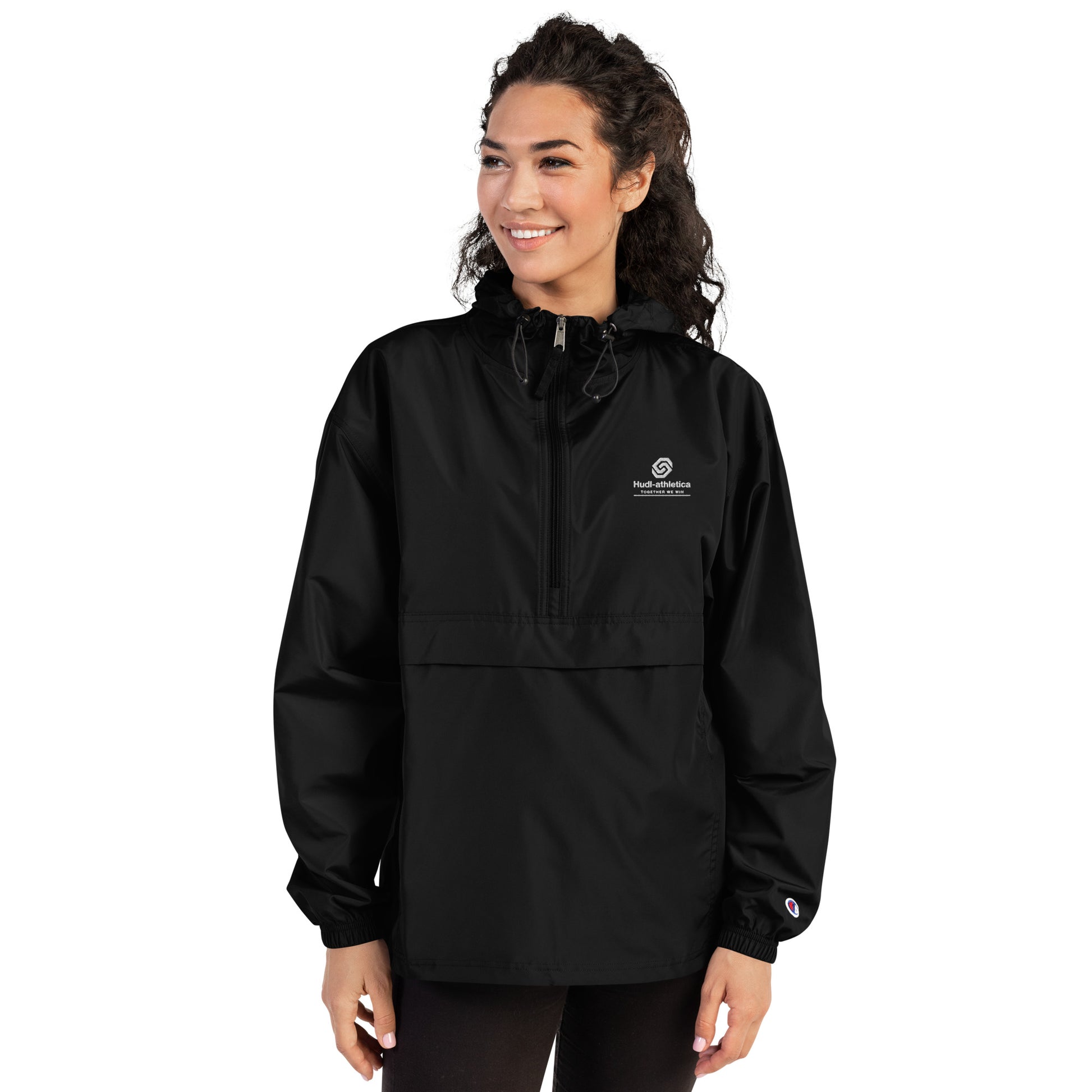 A woman wearing the HUDL lightweight packable windbreaker jacket – squash warm-up gear, embroidered logo in black