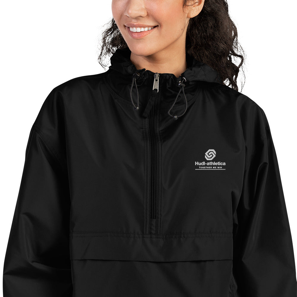 A close up of a woman wearing the HUDL lightweight packable windbreaker jacket – squash warm-up gear, embroidered logo in black