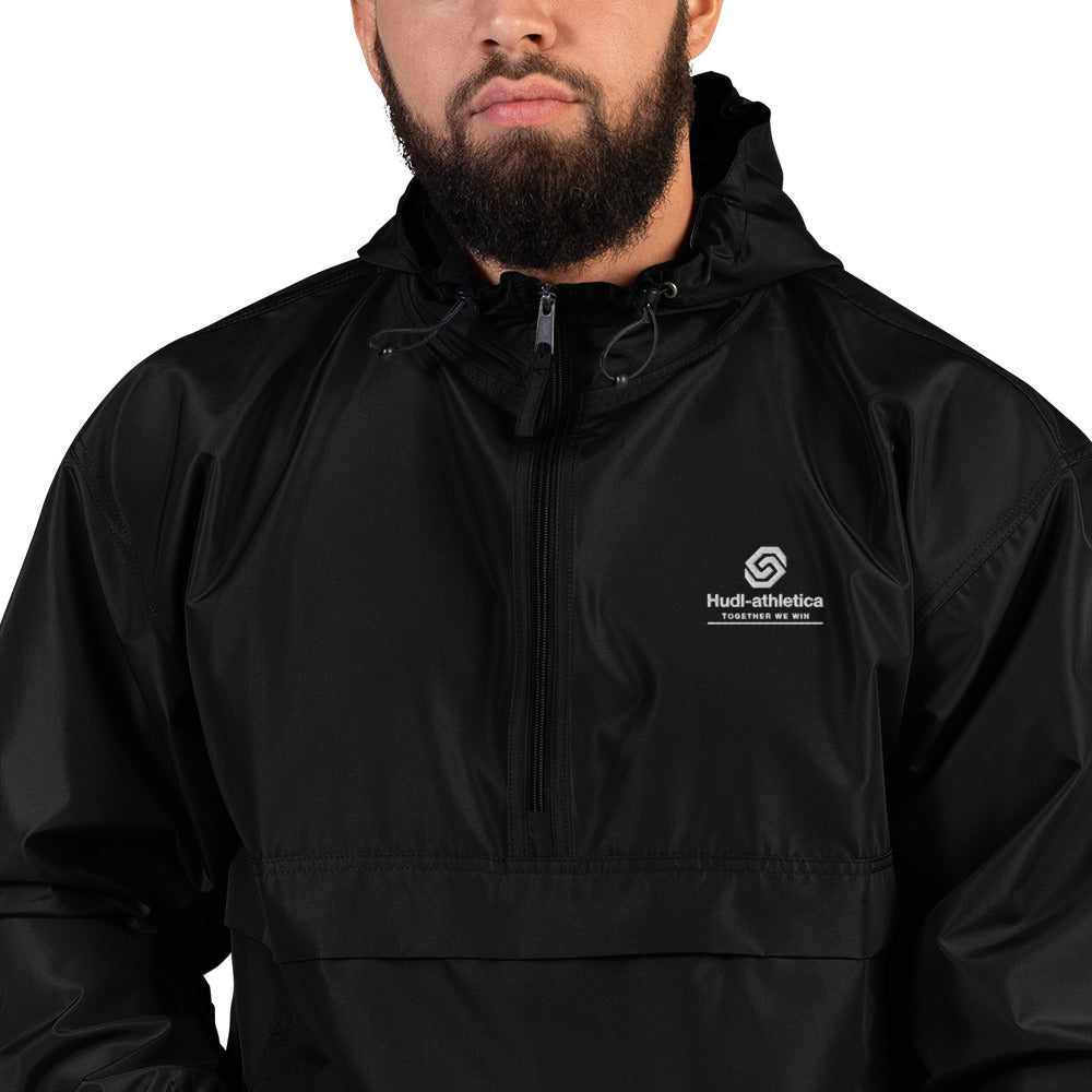 A close up of a man wearing the HUDL lightweight packable windbreaker jacket – squash warm-up gear, embroidered logo in black