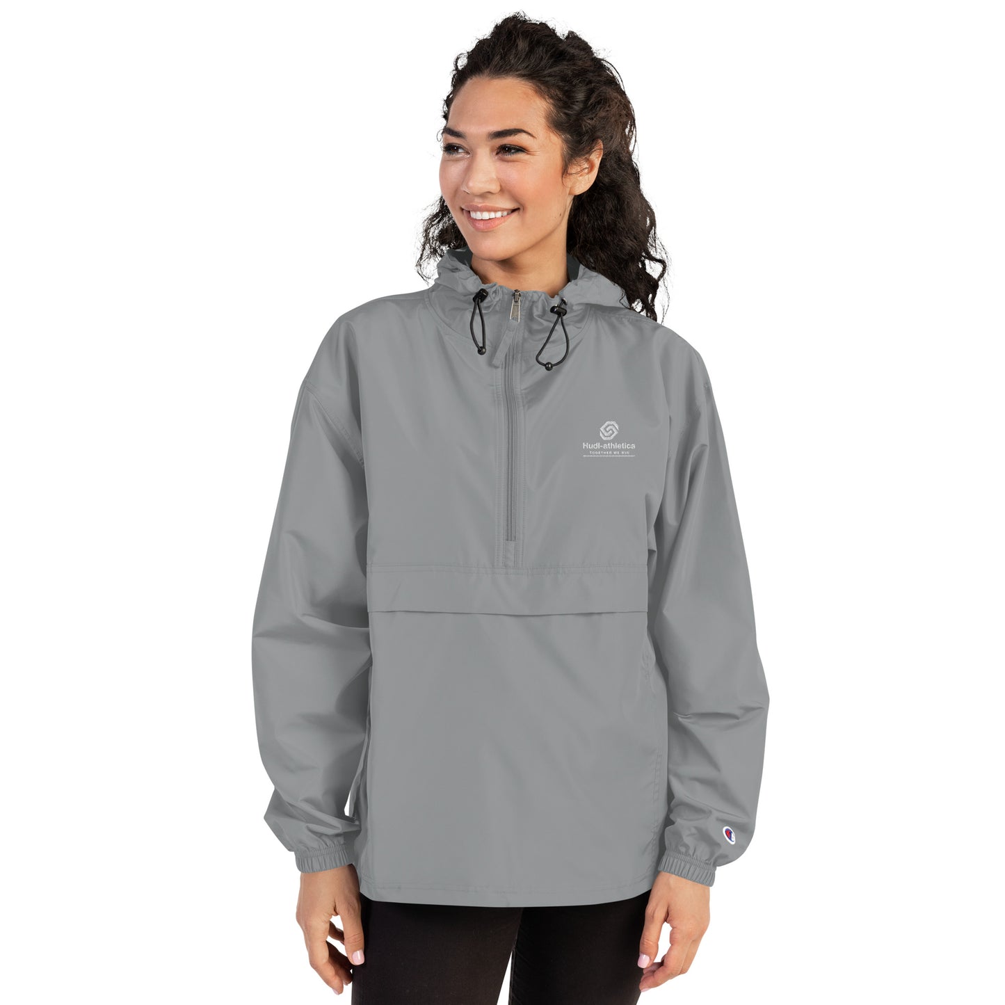 A woman wearing the HUDL lightweight packable windbreaker jacket – squash warm-up gear, embroidered logo in grey
