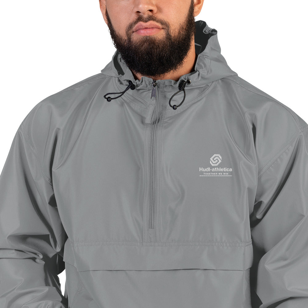 A close up of a man wearing the HUDL lightweight packable windbreaker jacket – squash warm-up gear, embroidered logo in grey