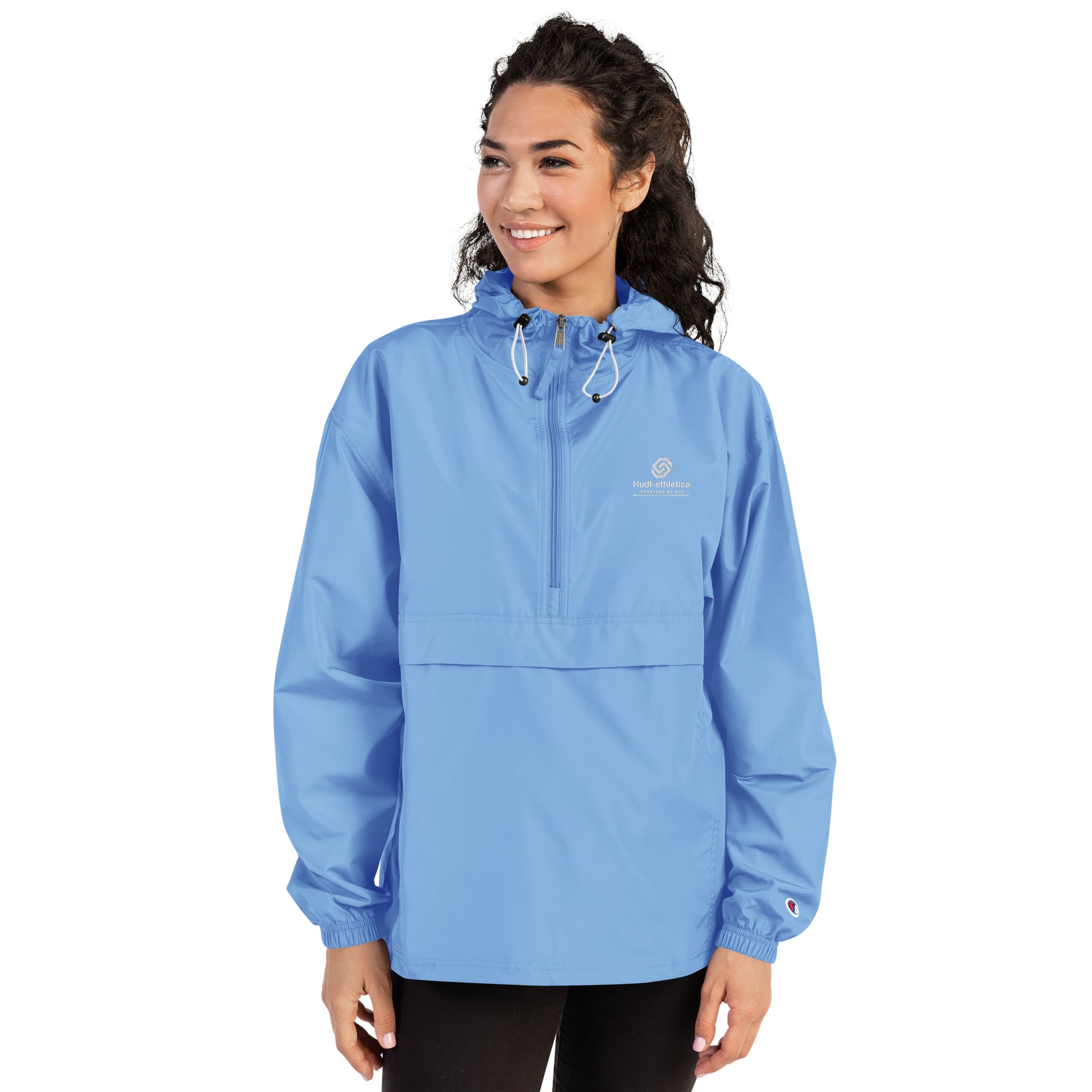 A woman wearing the HUDL lightweight packable windbreaker jacket – squash warm-up gear, embroidered logo in light blue
