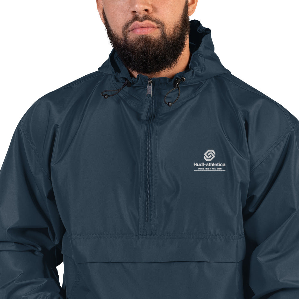 A close up of a man wearing the HUDL lightweight packable windbreaker jacket – squash warm-up gear, embroidered logo in navy