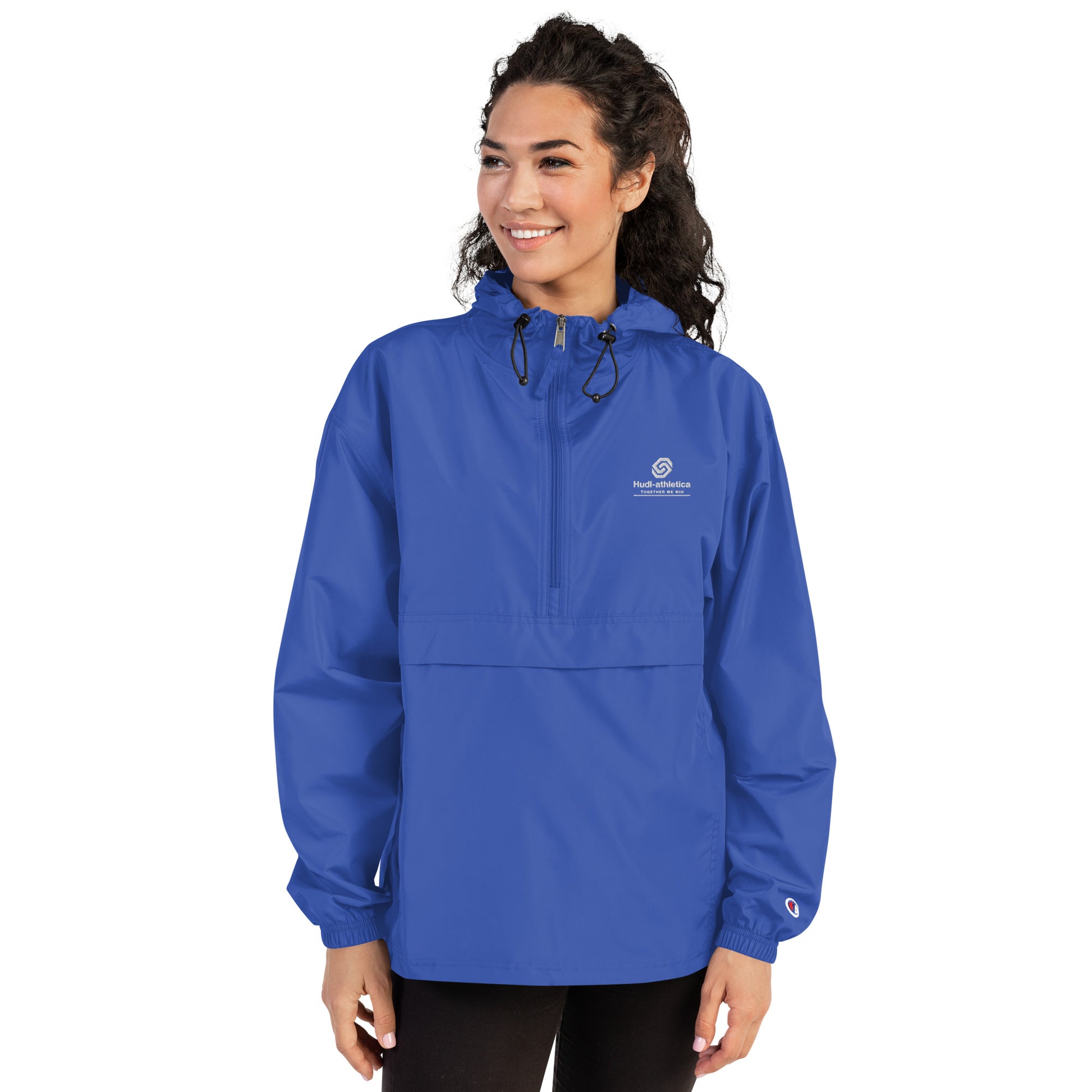 A woman wearing the HUDL lightweight packable windbreaker jacket – squash warm-up gear, embroidered logo in royal