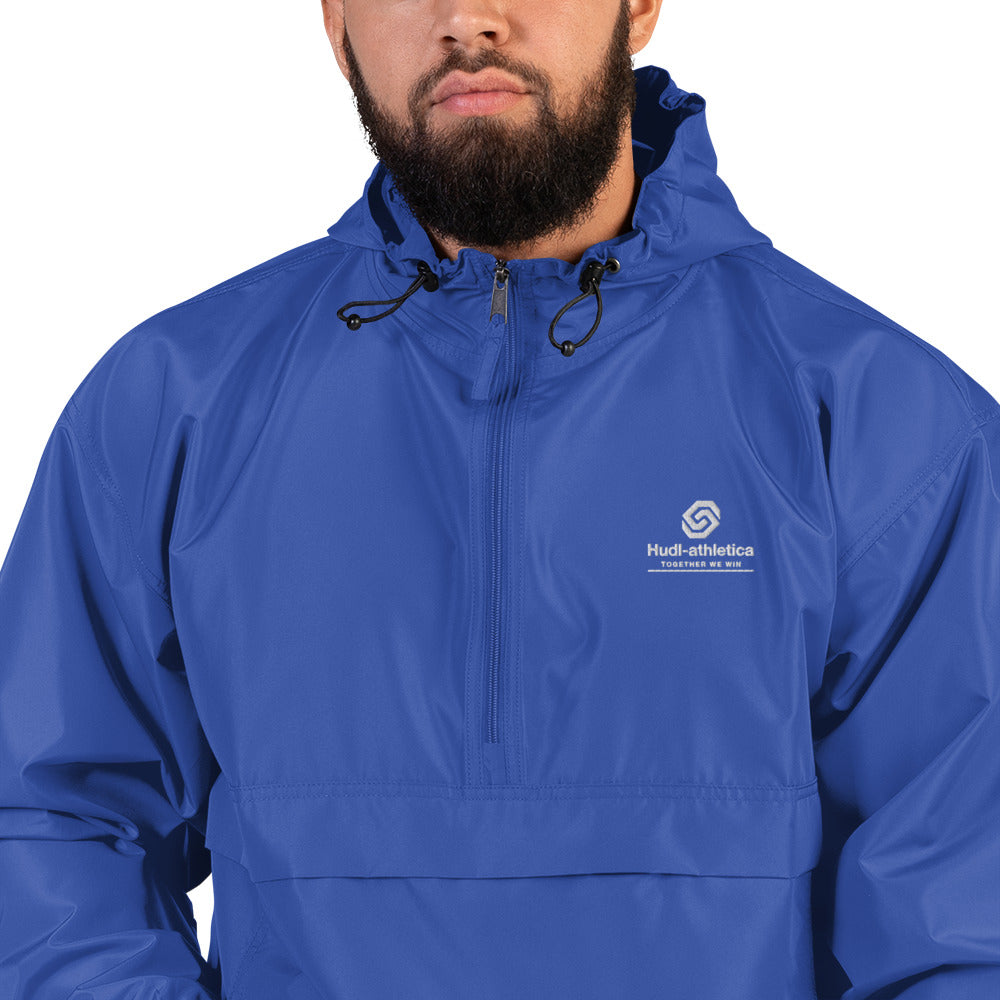 A close up of a man wearing the HUDL lightweight packable windbreaker jacket – squash warm-up gear, embroidered logo in royal
