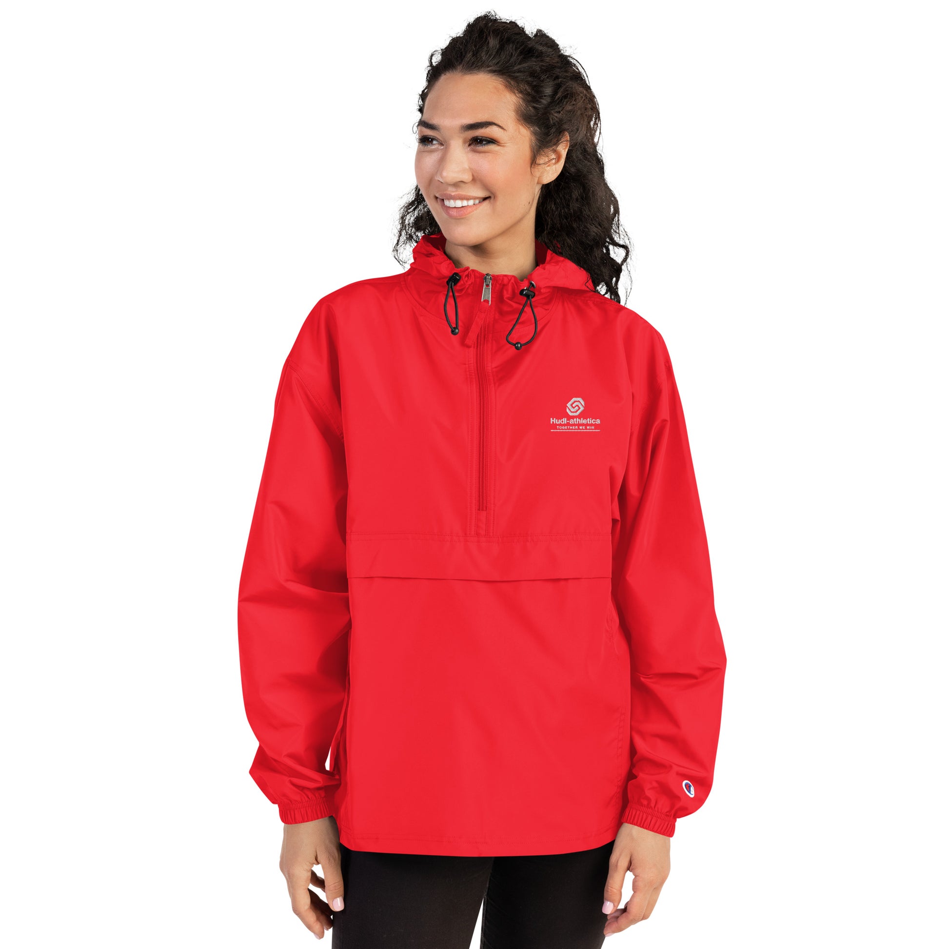 A woman wearing the HUDL lightweight packable windbreaker jacket – squash warm-up gear, embroidered logo in red