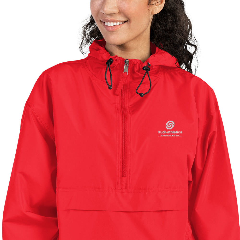 A close up of a woman wearing the HUDL lightweight packable windbreaker jacket – squash warm-up gear, embroidered logo in red
