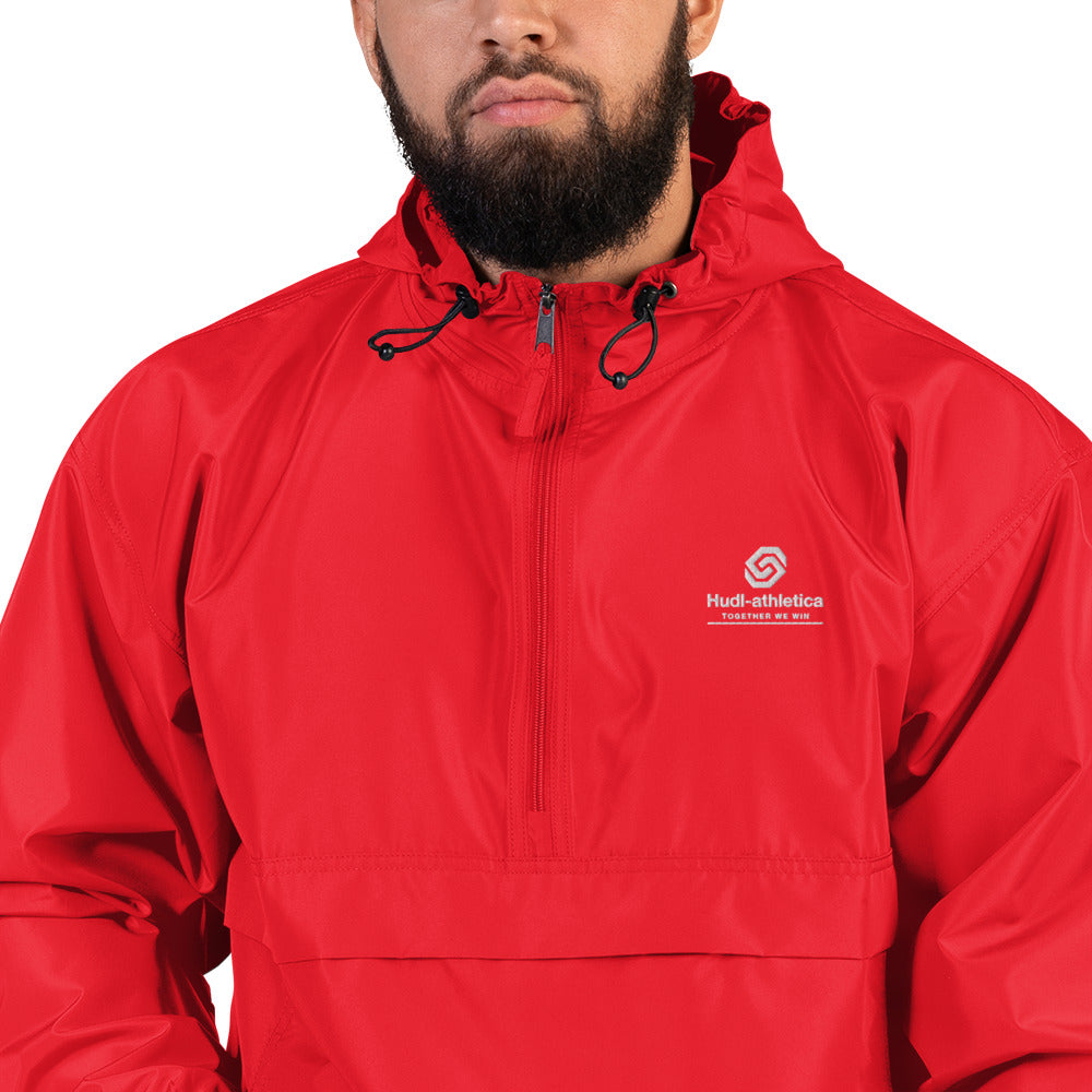 A close up of a man wearing the HUDL lightweight packable windbreaker jacket – squash warm-up gear, embroidered logo in red