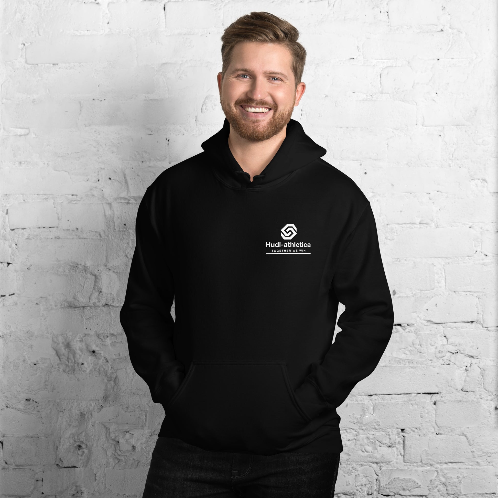 A man wearing a HUDL unisex pullover fleece hoodie – squash off-court essential, embroidered HUDL logo in Black 