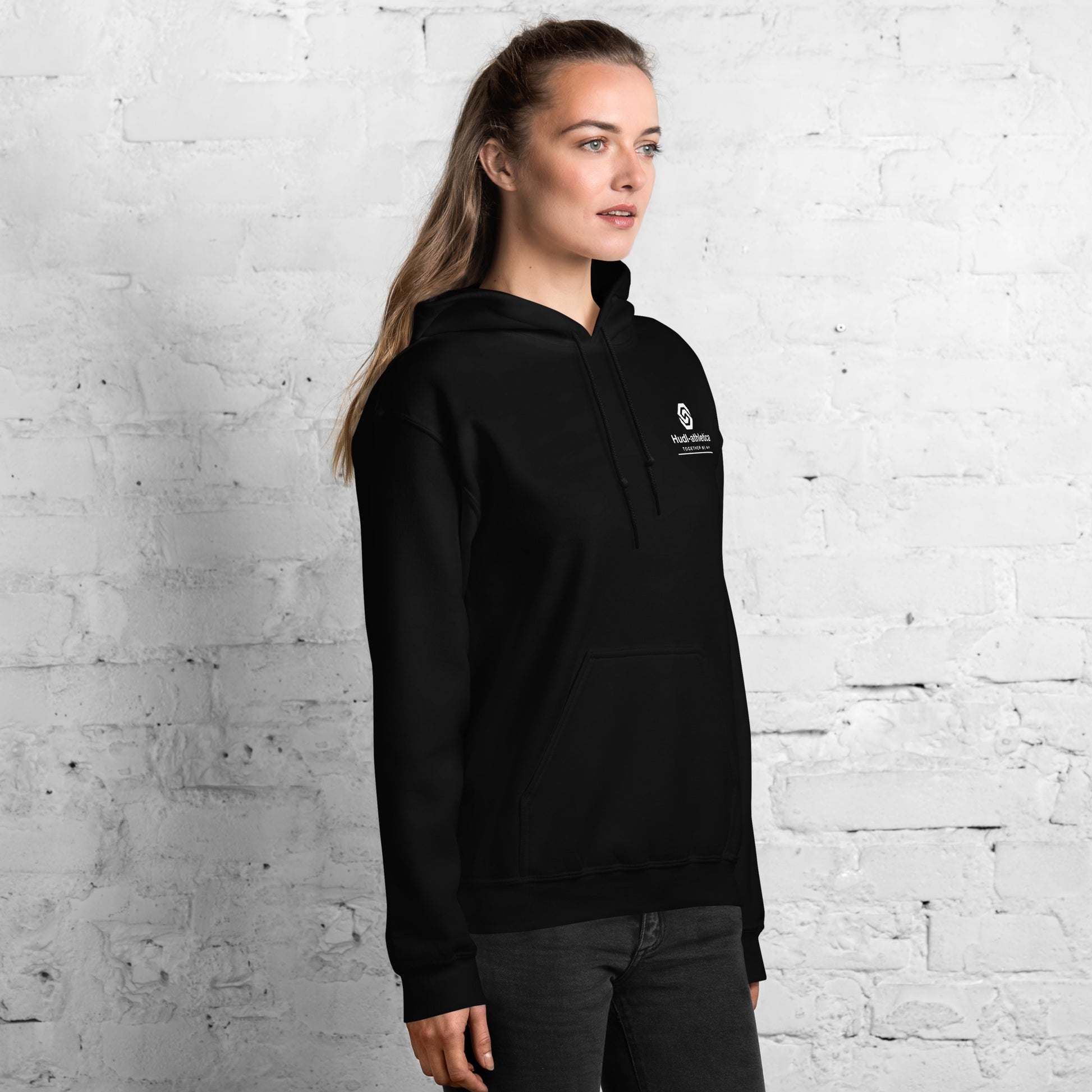 A woman wearing a HUDL unisex pullover fleece hoodie – squash off-court essential, embroidered HUDL logo in Black 