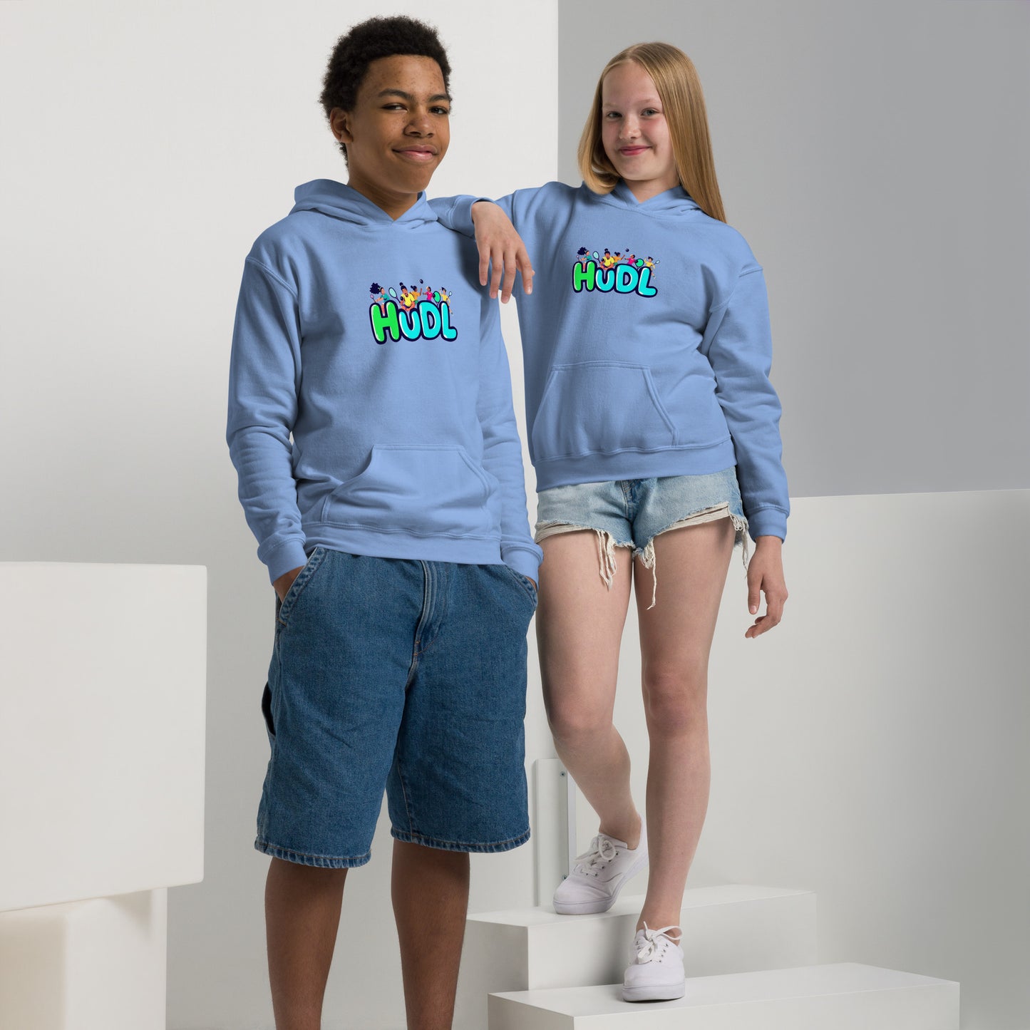 A boy and a girl standing and wearing a HUDL youth heavy blend hoodie – warm, durable off-court hoodie for junior squash players in sky blue